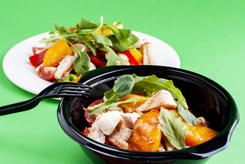 Salad with meat and peach in a plastic container
