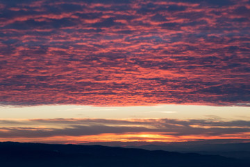 A surreal rooftop of red clouds, reflecting sunset light