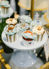 Set of stylish wedding cupcakes with cream cheese on white ceramic pedestal.