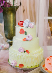 Obraz na płótnie Canvas A classic tiered wedding lemon cake with marshmallow flowers decoration on crystal pedestal.