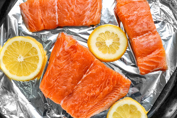 Raw slices of salmon and lemon on foil, closeup