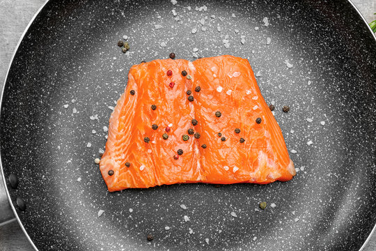 Frying pan with slice of salmon and spices, closeup