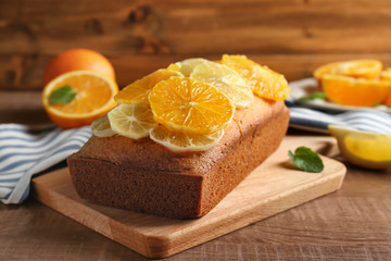 Naklejka na ściany i meble Cutting board with delicious citrus cake and sliced fruits on wooden table