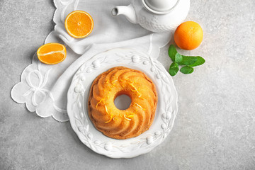 Plate with delicious citrus cake and orange zest on light table