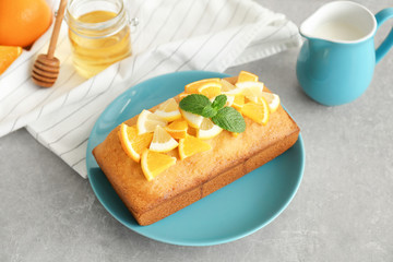 Plate with delicious citrus cake on grey table
