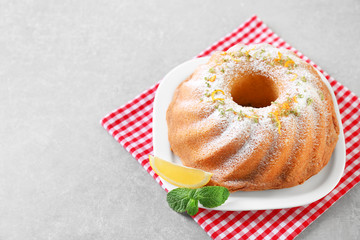 Plate with delicious citrus cake and lemon on table