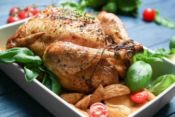 Baking dish with golden roasted turkey and vegetables on table