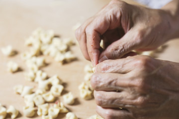 Side view woman's hands make Turkish Ravioli on table. Plates of traditional Turkish food. manti