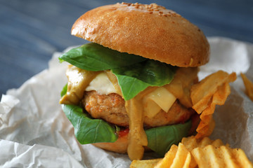 Tasty turkey burger with chips on table