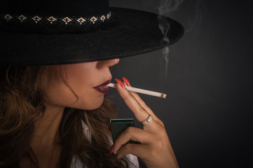 Obraz premium Portrait of sexy elegant lady woman with hat smoking cigarette