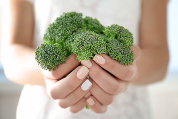 Naklejka na ściany i meble Fresh green broccoli in hands close-up