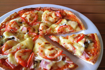 Ham and Tomato Pizza on a White Plate Served on Wooden Table 