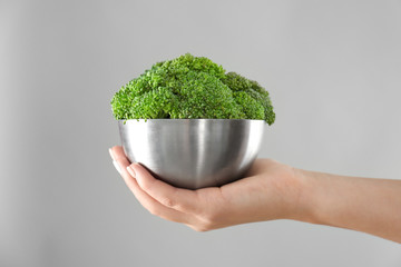 Fototapeta na wymiar Hand holding metal bowl with fresh green broccoli