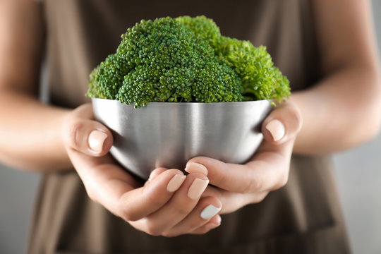 Hands holding metal bowl with fresh green broccoli