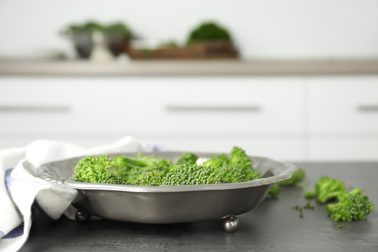 Fresh green broccoli sprouts on metal plate on kitchen table