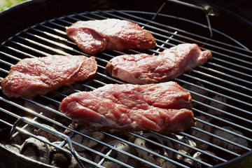 Raw tasty steaks cooking on barbecue grill, close up