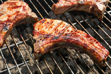 Tasty pork steaks cooking on barbecue grill outdoors, close up