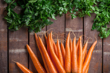 Carrot overhead group and green parsley leaves on old rustic wooden table in studio