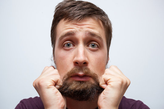 Young Bearded Man Pulling At His Long Messy Beard In Frustration