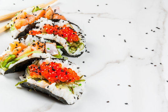Trend hybrid food. Japanese Asian cuisine. Mini sushi-tacos, sandwiches with salmon, hayashi wakame, daikon, ginger, red caviar. White marble table, with chopsticks, soy sauce. Copy space