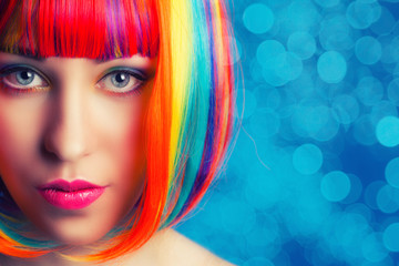 beautiful woman wearing colorful wig against blue background