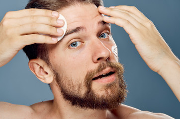 Obraz premium Man with a beard on a gray background, cosmetic cream, portrait, sponge