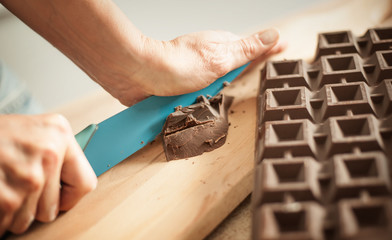 Woman hands chopping chocolate block for celebratory cake