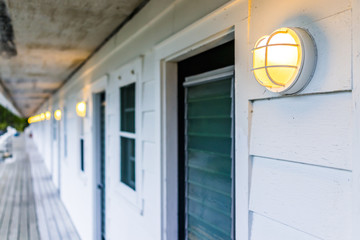 Row of hotel or motel doors outside with illuminated lights lamps in evening