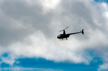 Fototapeta na wymiar helicopter flying to the left in the clouds above a blue sky