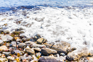 Rocky public beach called Ship Cove by Portland Head Lighthouse in Cape Elizabeth, Maine with closeup of water and stones on ground level