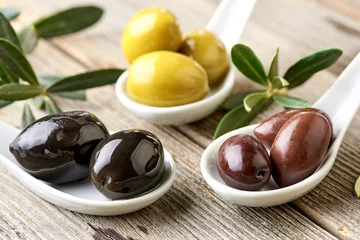 Foto op Plexiglas Different kind of olives green olives, black olives, kalamata olives and olive branch on wooden light table. Variations of olives. © Tatyana Sidyukova
