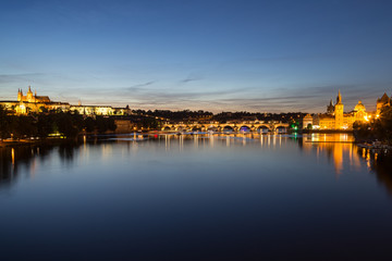 View of the lit Prague (Hradcany) Castle, Charles Bridge (Karluv most), buildings at the Old Town and their reflections on the Vltava River in Prague, Czech Republic, at night.