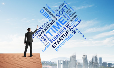 Young businessman standing on house roof and writing leadership skill concept. Mixed media
