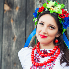 Fototapeta premium beautiful young woman wearing national ukrainian clothes sitting in wooden hut
