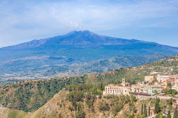 Fototapeta na wymiar Panoramic view of Etna volcano and beautiful town of Taormina in the foreground, Sicily island, Italy
