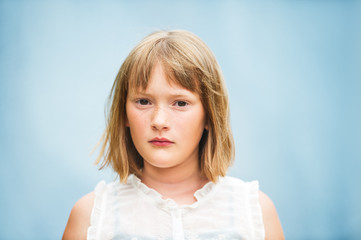 Close up portrait of adorable little girl with short bob haircut standing against blue background