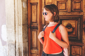 Funny little girl traveler walking on the streets of Provence, wearing backpack. Travel with kids, family vacation on south of France, image taken in Aigues-Mortes, Camargue