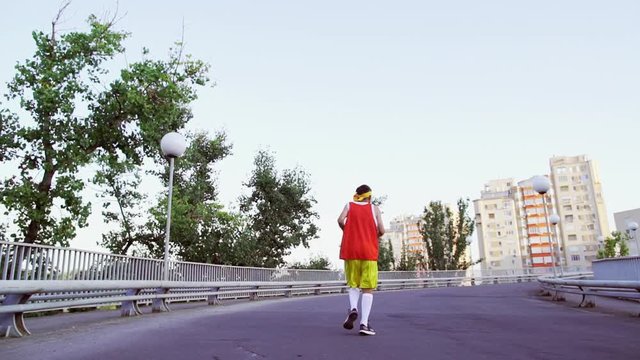 Funny thin guy in sports clothes jogging on the bridge in the morning.