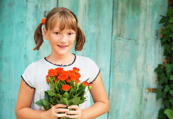 Outdoor portrait of a yong little girl of 9 years old, wearing white dress, holding fresh bouquet of beautiful orange roses