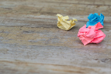 Three coloured (yellow, blue and pink) crumpled paper ball in wooden background. Creativity crisis concept. Set of crumpled paper balls.