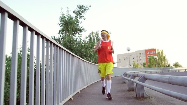 Funny thin guy in sports clothes jogging on the bridge in the morning.