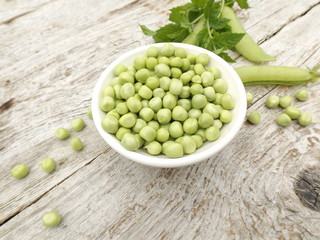 Peeled young green peas in a bowl and a bunch of mint