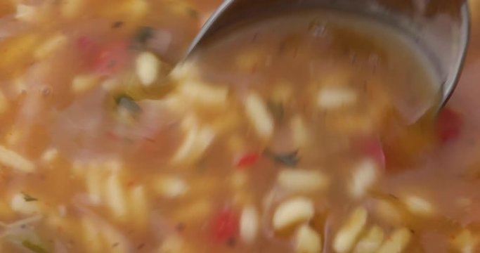 Stirring gumbo with a spoon while heating.