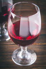 Two glasses of red wine on a brown wooden table. Alcoholic beverages.