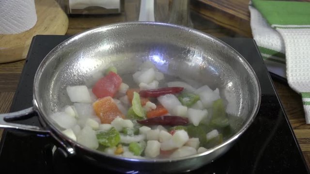 Pouring frozen vegetables into a frying pan and stirring