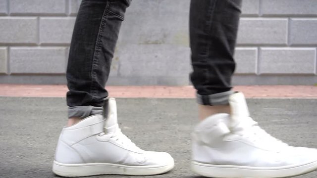Shot of men legs in sneakers walking on tile road.