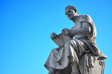 Statue of a man reading in Italy with blue sky