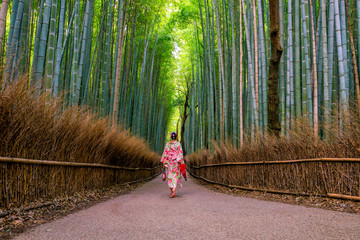 Woman in traditional Yukata with red umbrella at bamboo forest of Arashiyama