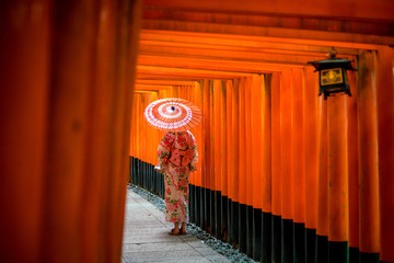 Fille japonaise en Yukata avec parapluie rouge au sanctuaire Fushimi Inari