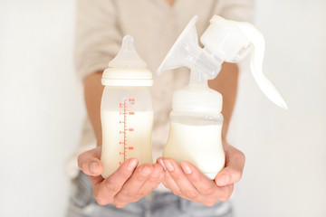 Breast pump and bottle with milk in woman's hand - 168688381